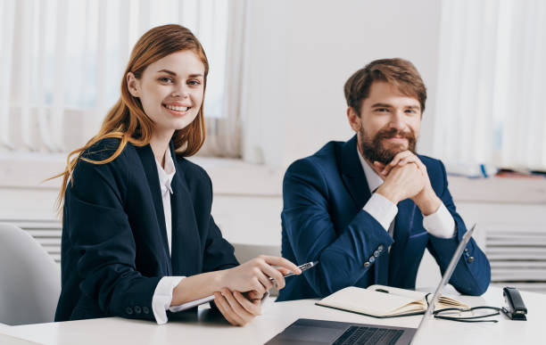 istock business man and woman sit at the table with open laptop in office and notepad documents model 2126861675