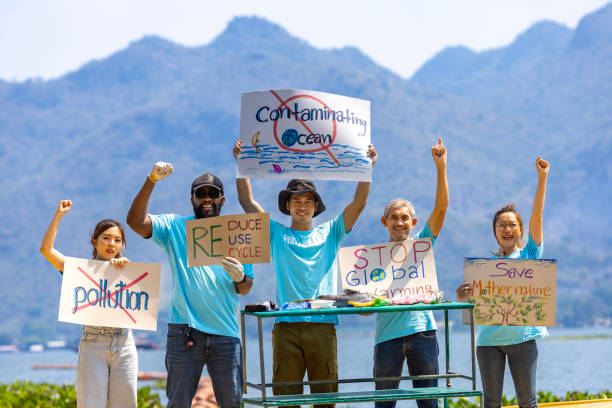 Team of ecologist volunteers are demonstrating rally at ocean for climate change and saving nature with protest sign against pollution and sea contamination for wildlife and biodiversity Team of ecologist volunteers are demonstrating rally at ocean for climate change and saving nature with protest sign against pollution and sea contamination for wildlife and biodiversity proteciton Senior Volunteering: Making a Difference at Any Age stock pictures, royalty-free photos & images