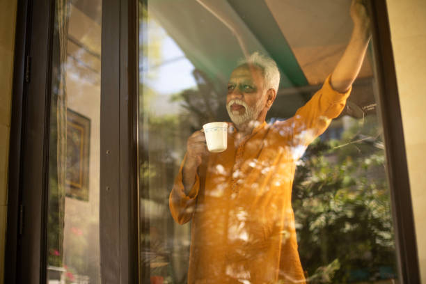 istock Thoughtful retired elderly man with coffee cup at window 2126893018