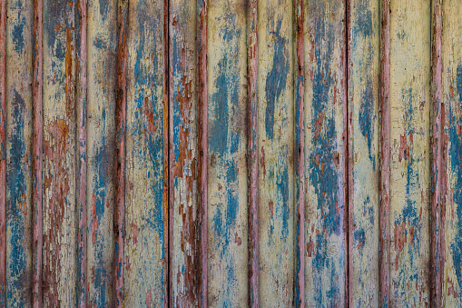 Artistic old wooden planks board texture with peeled brown and blue paint layers under sun-bleached blue paint layer. Full-frame flat background and texture.
