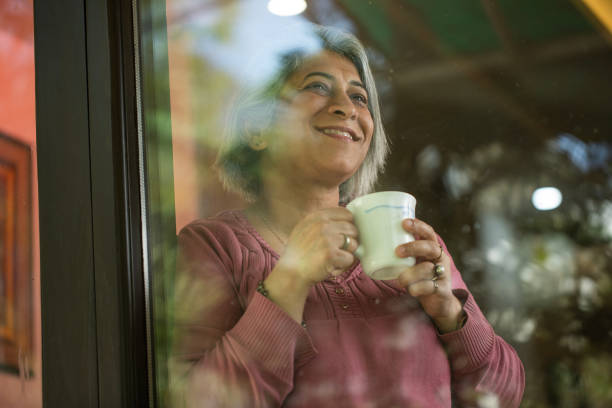 istock Thoughtful retired elderly woman with coffee cup at window 2126904370