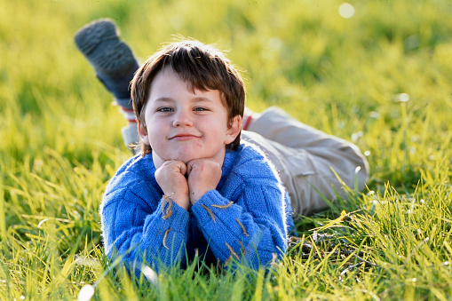 Portrait of a smiling young boy lying in the grass