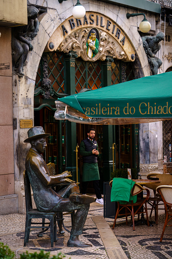 Statue of a Man Sitting at a Table in Front of A brasileira do chiado. Lisbon, Portugal. February 2, 2024.