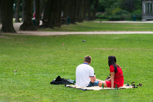 Brussels, Belgium - July 4, 2015: A couple sitting on the grass, enjoying the Cinquantenaire Park, near the Palace of the same name.