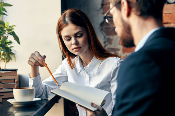 Mature man and mid adult woman signing papers and writing with pens