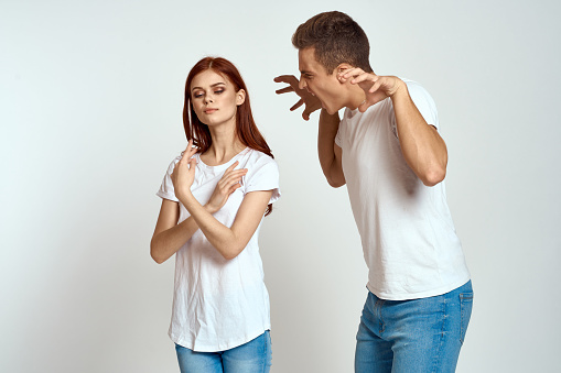 family couple in love jeans white t-shirt emotions fun man and woman having fun on a light background gesturing with their hands. High quality photo