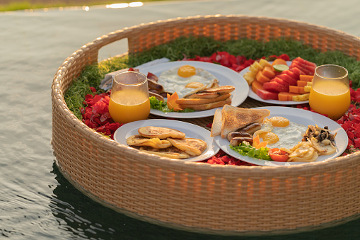 Close up float basket with breakfast on swimming pool