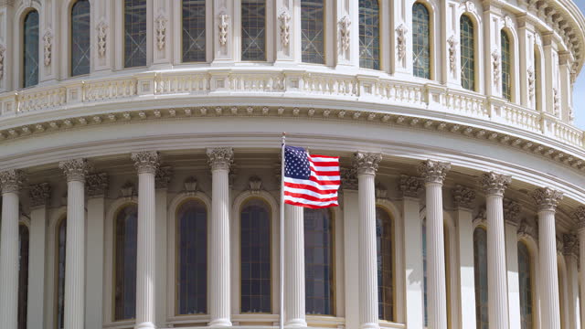 The national flag of USA in front of The United States Capitol Building background in Washington, D.C., Pennsylvania, United States