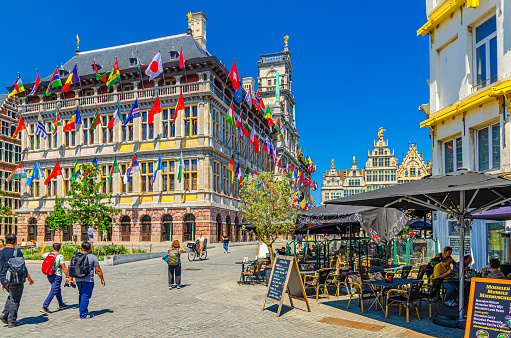 Antwerp, Belgium, July 7, 2023: City Hall Stadhuis building with european countries flags and street restaurants cafes with people tourists in old town Antwerpen city historical centre
