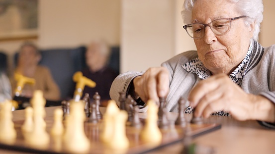 Two senior friends playing chess board game in a geriatric