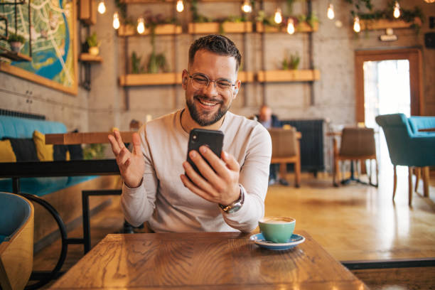 istock Happy man having video chat via smartphone in cafe 2127110965