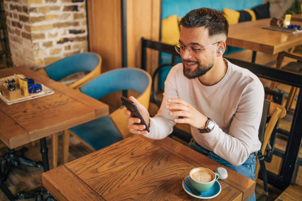 istock Happy man having video chat via smartphone in cafe 2127110966