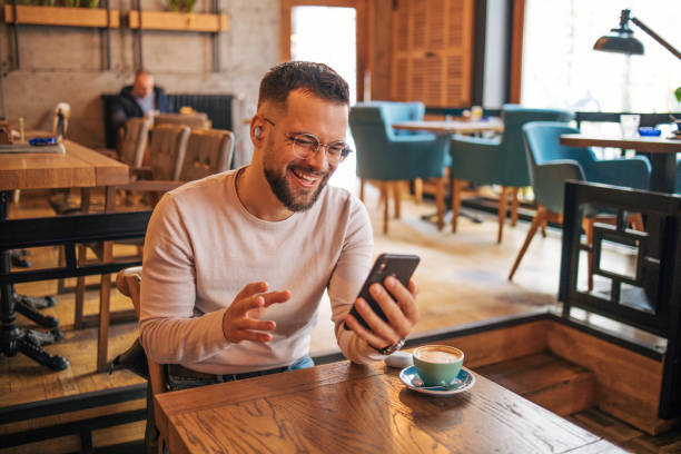 istock Happy man having video chat via smartphone in cafe 2127113058