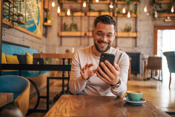 istock Happy man having video chat via smartphone in cafe 2127113511