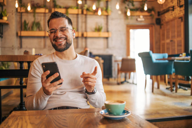 istock Happy man having video chat via smartphone in cafe 2127118617