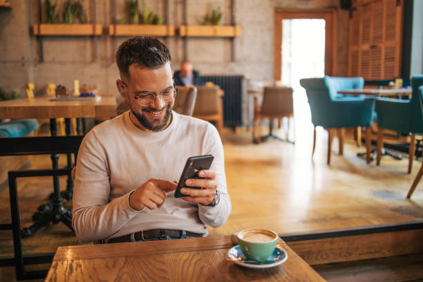 istock Happy man having video chat via smartphone in cafe 2127123408