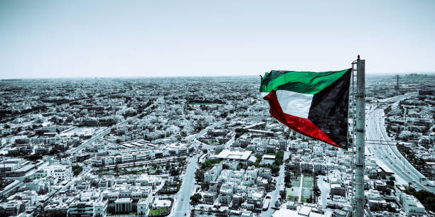 istock Kuwait flag waving in the wind over the cityscape 2127126507