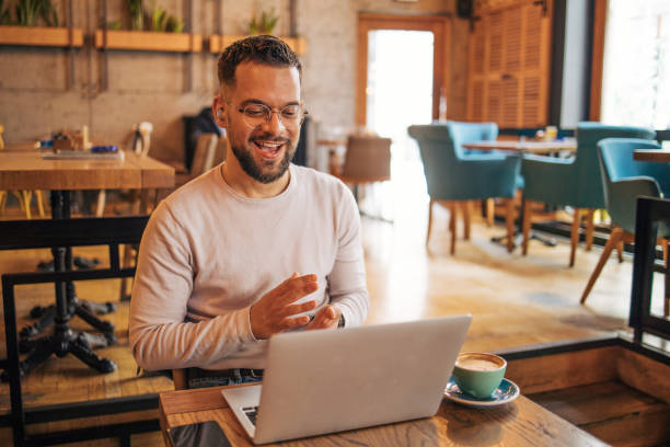 istock Young businessman using laptop and having video call at coffee shop 2127130419