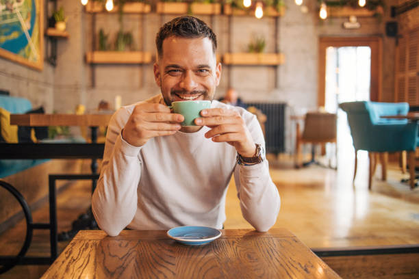 istock Happy man sitting and drinking coffee from green cup 2127168006
