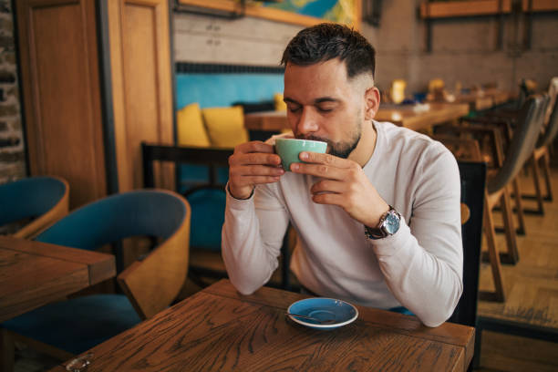 istock Happy man sitting and drinking coffee from green cup 2127172103