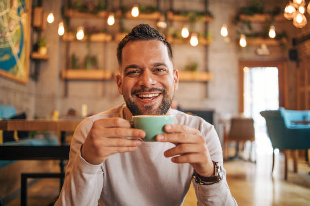 istock Happy man sitting and drinking coffee from green cup 2127172104