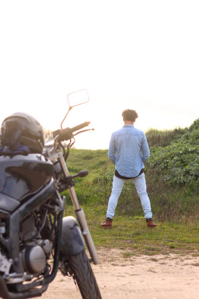 istock Curly haired Caucasian young man peeing in with parked motorcycle 2127175698