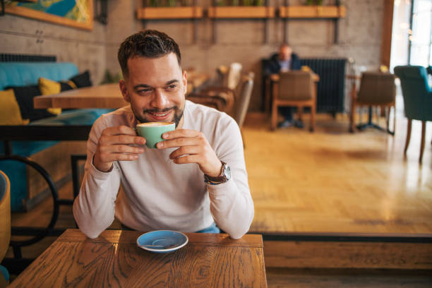 istock Happy man sitting and drinking coffee from green cup 2127176224