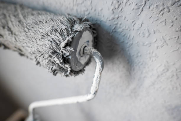 istock Paint roller extendable pole over painted woodchip wallpaper wall during home renovation in england uk 2127215614