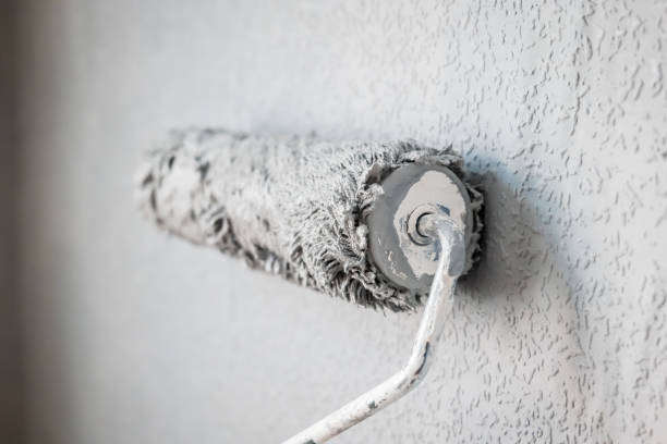 istock Paint roller extendable pole over painted woodchip wallpaper wall during home renovation in england uk 2127215625