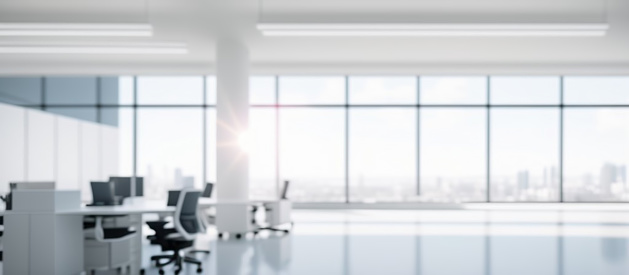 Defocused blurred interior of a bright modern spacious office with panoramic windows and sunlight.