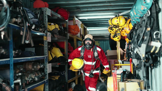 Asian Firefighter in Rapid Preparation Amidst Equipment for an Upcoming Training Exercise