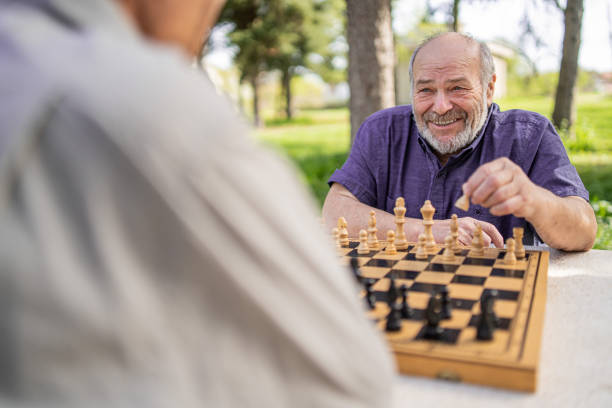 istock Chess, nature and retirement with senior friends playing a boardgame while bonding outdoor during spring. 2127352486
