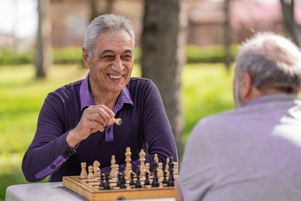 istock Chess, nature and retirement with senior friends playing a boardgame while bonding outdoor during spring. 2127352499