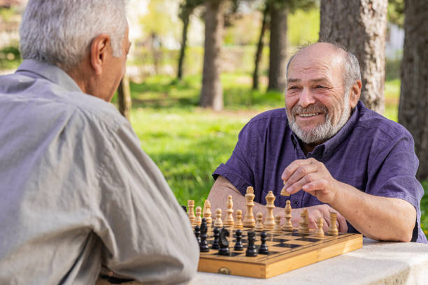 istock Chess, nature and retirement with senior friends playing a boardgame while bonding outdoor during spring. 2127352504