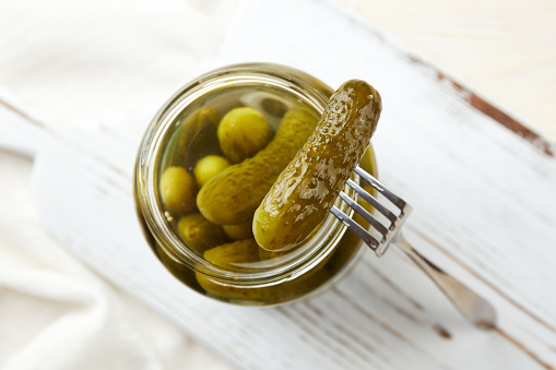 Marinated cucumbers in a jar on a light wooden background. Homemade pickles.