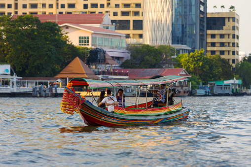 Bangkok, Thailand - 29 December, 2023: tourists ride on a wooden longtail boat decorated with flower garlands on the Chao Phraya River at Bangkok, Thailand