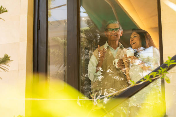 istock Happy senior couple with coffee cups talking at window 2127444048