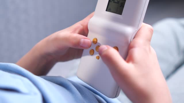 close-up A boy presses bright yellow buttons on a console game in a white case