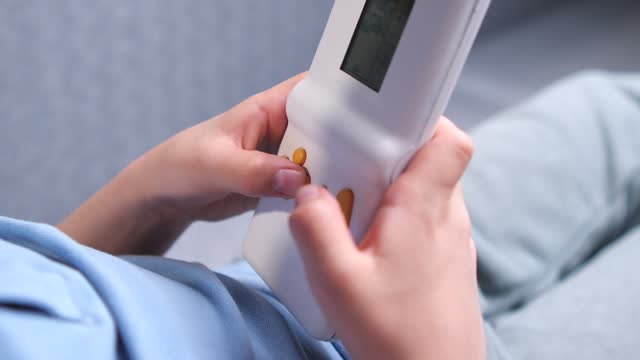 close-up A boy presses bright yellow buttons on a console game in a white case