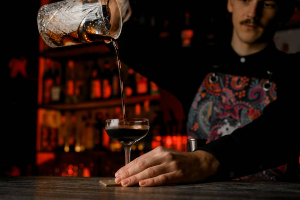 istock Bartender pours a brown cocktail from a mixing glass with an ice strainer inserted 2127460042