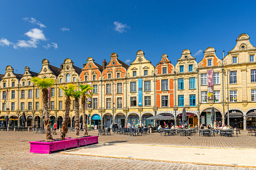 Arras, France, July 3, 2023: Flemish-Baroque-style townhouses on La Petite market Place des Heros Heroes Square in historical city center, blue sky in summer day, Artois, Hauts-de-France Region
