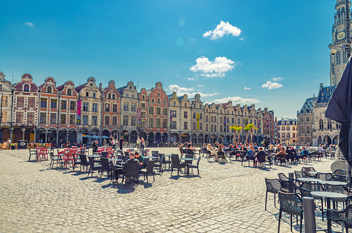 Arras, France, July 3, 2023: Flemish-Baroque-style townhouses and street restaurants on Place des Heros Heroes Square in historical center, blue sky in summer day, Artois, Pas-de-Calais department