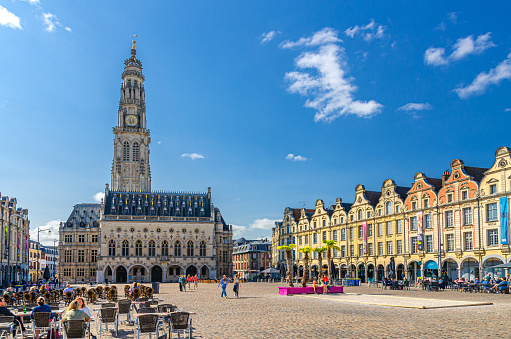 Arras, France, July 3, 2023: Hotel de Ville town hall building with belfry bell tower, Flemish-Baroque-style townhouses buildings on Heroes Square in historical center, Artois, Hauts-de-France Region