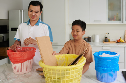 Proud father teaching son to sort and categorize trash