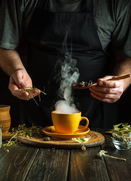 A man prepares tea from the medicinal plants rosehip and chamomile on the kitchen table. Traditional medicine concept at home
