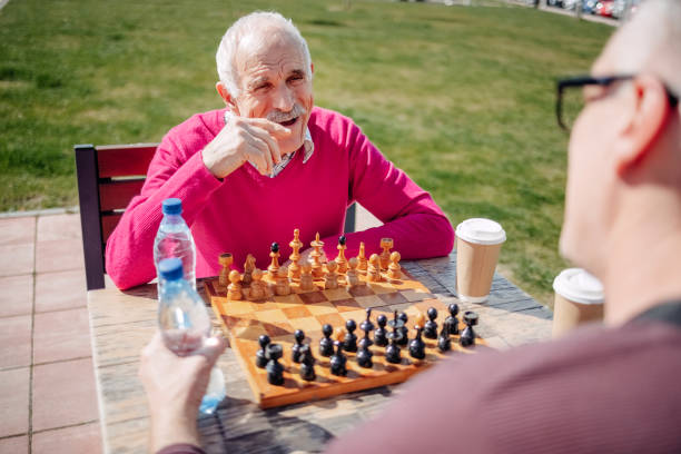 istock Old man enjoying playing chess outdoors on beautiful sunny day 2127562287