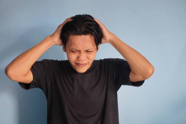 istock young asian man grabbing his head showing stress gesture. 2127580191