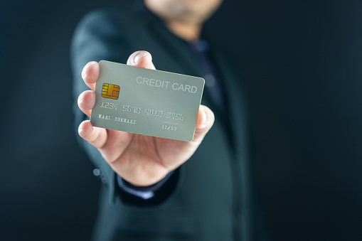 Businessman holding a white credit card while standing. Mock up copy space. Holding credit bank card