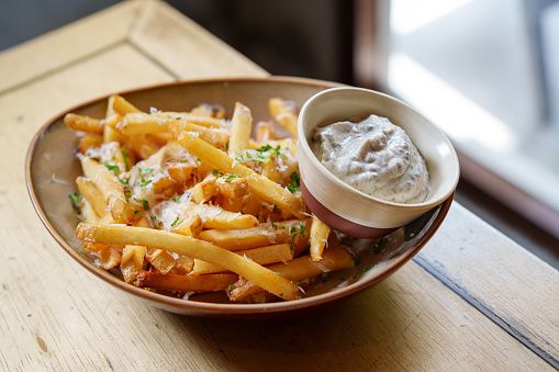 A plate of fries chips topped with parmesan cheese and truffled mayonnaise is a delicious and indulgent snack or side dish.