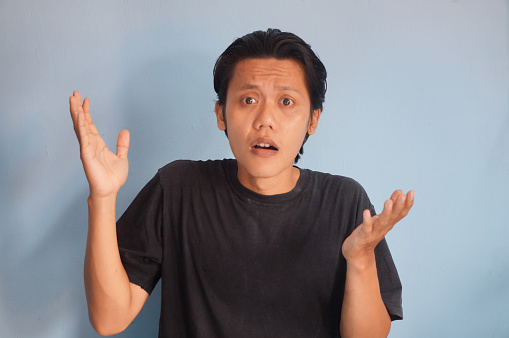 Young Asian man wearing black t-shirt showing confused facial expression